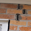 A brick wall displaying stair-step cracks and messy tuckpointing on a Scottsdale home
